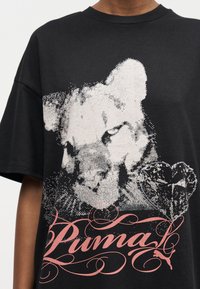 Μαύρο μπλουζάκι με λευκό αφηρημένο πρόσωπο πούμα, γραφικό διαμάντι και στυλιζαρισμένο ροζ κείμενο «Puma» στο μπροστινό μέρος.