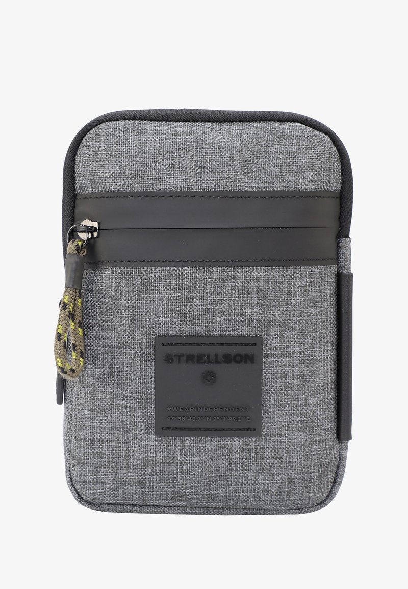 Siva tkaninska torba z teksturirano površino, opremljena z črnim usnjenim trakom, z zadrgo in pletenim povodcem ter nalepko z logotipom.