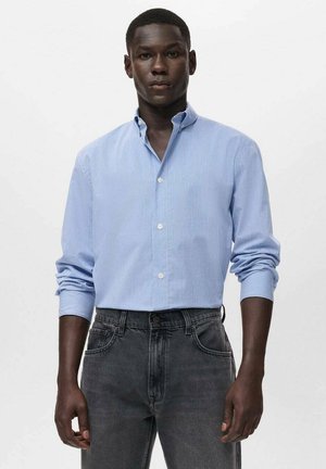 Light blue striped button-up shirt with a collar, long sleeves, and white buttons, paired with dark gray jeans. Smooth fabric texture.