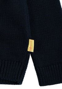 Maglione lavorato a maglia di colore blu navy con una texture a coste. Presenta un'etichetta gialla con scritte rosse. Il design include uno stile a spalla cadente.