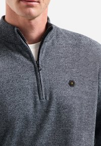 Grijze rits-fleece sweater met hoge kraag, voorzien van een gestructureerde stof en een klein zeshoekig logo op de linkerborst.