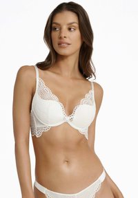 White lace bra with a sheer scalloped trim, underwire support, and adjustable straps. Smooth cups contrasted by intricate lace detailing.
