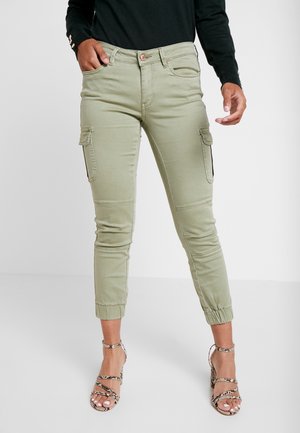 Ljusgröna cargobyxor med sidofickor, smala muddar och en slät yta. Bärs med strappy sandaler i neutrala nyanser.