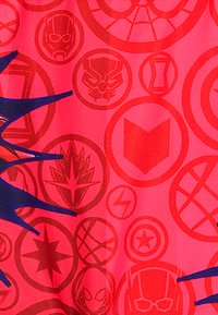 Rode stof met verschillende superheldenemblemen en logo's in tinten van rood en blauw, met een gladde textuur en een herhalend cirkelontwerp.
