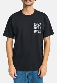 Sort bomulds T-shirt med et hvidt grafisk logo på venstre brystområde. Løs pasform med korte ærmer og rund halsudskæring.