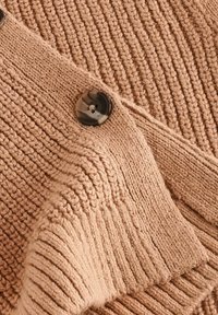 Cardigan lavorato a maglia in beige chiaro, con costine testurizzate, colletto ripiegato e un grande dettaglio con bottone scuro. Tessuto morbido e accogliente.