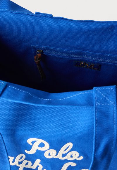 Μπλε τσάντα tote από καμβά Polo Ralph Lauren με εσωτερική τσέπη με φερμουάρ και δερμάτινο έλασμα για το φερμουάρ.