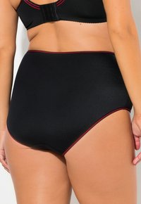 Zwarte high-waisted onderbroek met een gestructureerd patroon, accentueert met een dunne rode rand langs de tailleband en beenopeningen.