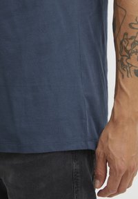 Marineblå bomull T-skjorte med glatt tekstur, korte ermer og en side-seam detalj, kombinert med mørke jeans.