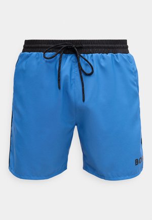 Blå badebukser med elastisk svart midjebånd og snor. Har sidepaneler med svarte detaljer og trykt logo nederst til høyre.