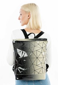 Zwarte en grijze rugzak met geometrisch patroon en glanzende afwerking, vierkante vormen, bovenhandgreep en verstelbare schouderbanden. Inclusief merklogo.