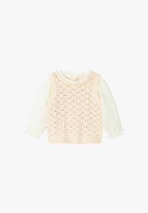 Cream-colored long sleeve blouse with ruffled cuffs under a sleeveless beige knitted vest featuring a diamond pattern.