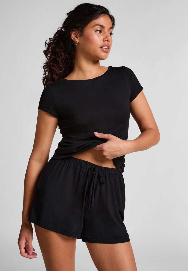 Haut noir à manches courtes et shorts assortis en tissu doux. Les shorts présentent une taille élastique avec un cordon de serrage. Design simple et décontracté.