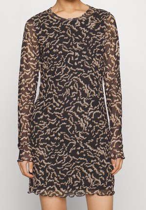 Woman wearing a long-sleeve sheer black dress with an abstract wavy leopard print in beige and white.