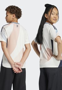 Korte mouwen sportshirts in een lichte kleur met abstracte roze en blauwe patronen, voorzien van een mesh-textuur en een marineblauw accent op de mouwen.