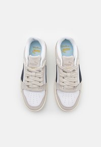 Tenisky s koženým a textilním svrškem, s bílou špičkou, béžovými akcenty a námořnickými bočními pruhy. Silné tkaničky a polstrovaný jazyk.