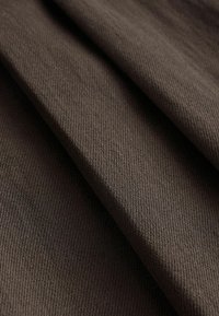 Tissu marron foncé avec une texture tissée en diagonale, présenté en plis doux mettant en valeur son épaisseur et sa texture.