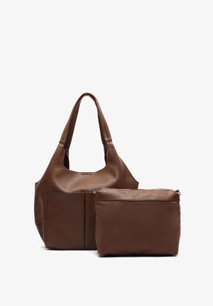 Sac fourre-tout en cuir marron avec une texture lisse et un design souple, comprenant une pochette zippée de la même couleur, les deux présentant des courbes douces.