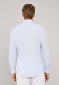 Camisa de manga larga azul claro con una textura suave, puños abotonados y un cuello clásico; acabado liso con un patrón sutil.