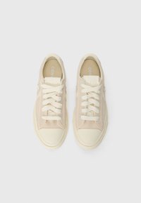 Béžové semišové tenisky s krémovými gumovými podrážkami, s kulatou špičkou, plochými tkaničkami a logem na jazyku a straně.