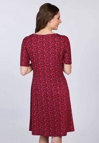 Kleid mit kurzen Ärmeln aus rotem Stoff, das ein kleines Blumenmuster aufweist, einen taillierten Oberteil und einen ausgestellten Rock präsentiert, mit einer weichen Textur und klassischem Stil.