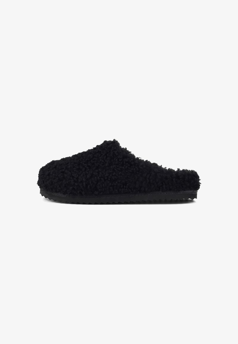 Black fuzzy clogs made from soft material with a textured surface. They have a cushioned footbed and a rubber outsole with a zigzag pattern.