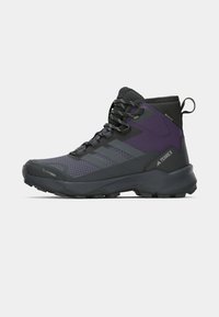 Black and purple hiking boots with a high ankle design, textured surface, and rubber outsole featuring deep grooves for traction.