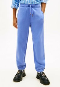 Lyseblå joggebukser med elastisk talje og manchetter. Har sidelommer og broderet logo. Sammen med sorte loafers.