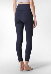 Leggings navy con vita alta, caratterizzati da una texture liscia e un design aderente. Gli orli sono cuciti e il materiale appare elastico.