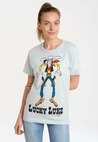 Light blue cotton t-shirt featuring a colorful cartoon character print of Lucky Luke. Short sleeves and a round neckline.