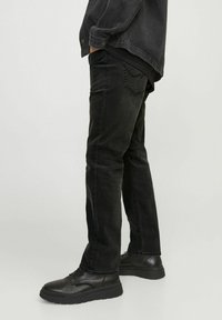 Svarta denimjeans med rak passform, utrustade med en klassisk fem-ficksdesign och subtila blekningar, tillsammans med svarta snörskor.