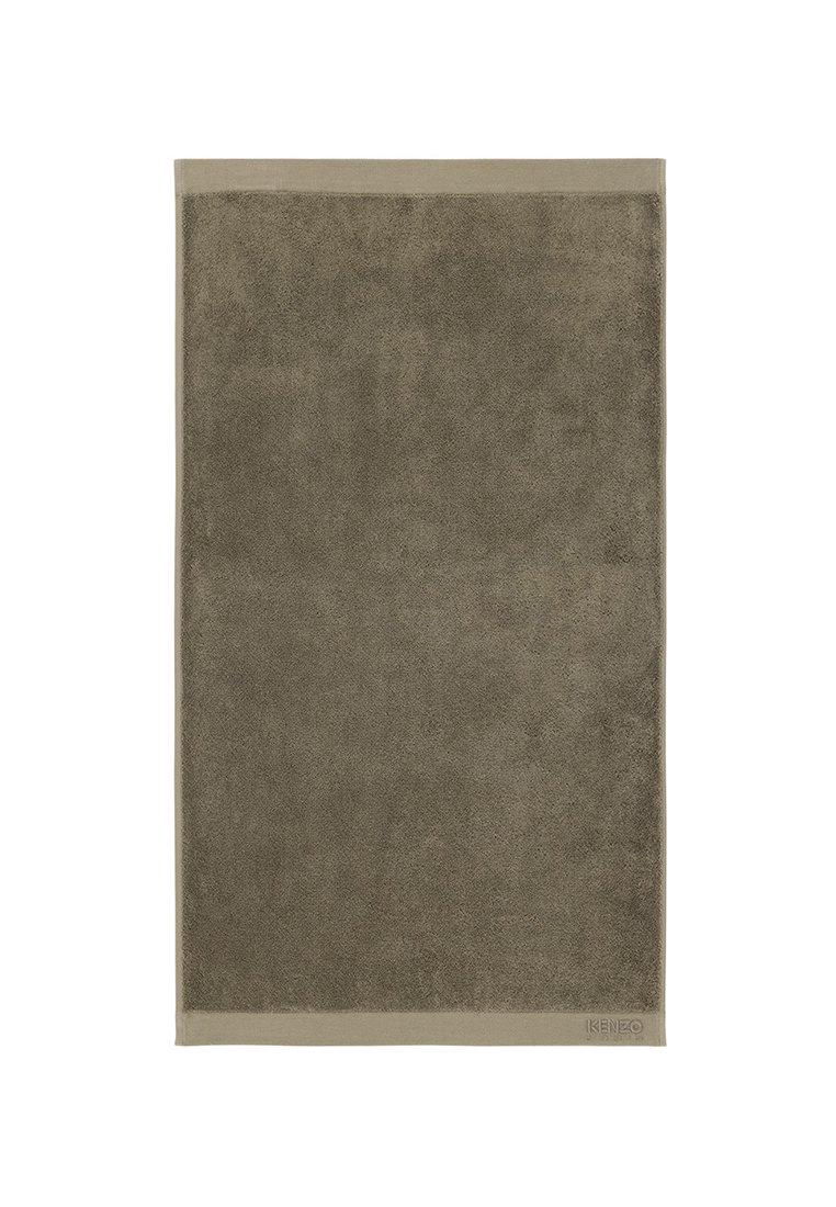 Serviette de bain taupe avec une surface de texture, bordée d'un bord lisse de taupe plus clair ; présente un logo de marque discret dans le coin.