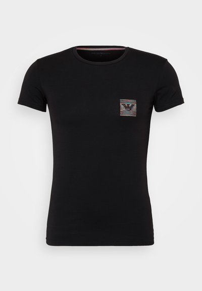 T-shirt en coton noir avec un col rond et des manches courtes. Présente un petit patch logo coloré sur la zone de la poche poitrine gauche.