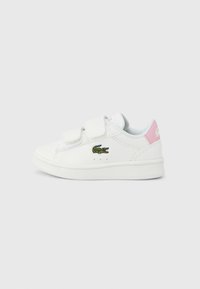 Baskets blanches avec fermetures Velcro, présentant un logo crocodile vert brodé, un accent rose au talon, et un matériau synthétique lisse.