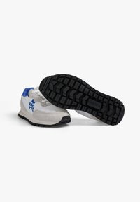 Zapatillas de running con parte superior de cuero blanco y ante gris, detalles azules, suela de goma negra con surcos profundos para tracción.