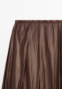 Hnědá saténová plisovaná sukně s hladkou texturou. Má jednoduchý pas a volný střih. Bez viditelných vzorů nebo ozdob.