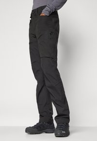 Sorte utendørsbukser med glidelåslomme, tapered passform og forsterkede knær. Laget av lett, slitesterkt stoff med matte overflate.