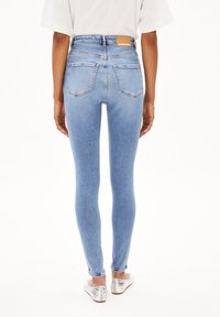 Högmidjade blå skinny jeans med ljus tvätt, som har en texturerad denimyta, bakfickor och en brun läderlogotyp.