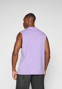 Chemise en coton lavande sans manches avec un col rond et une coupe décontractée, associée à un short noir texturé.