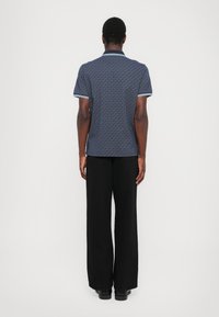 Ναυτικό πουκάμισο κοντομάνικο με σχέδιο, με αντίθετη κόψη και λεπτομέρειες στα μανίκια, συνδυασμένο με φαρδιά μαύρα παντελόνια. Λείο υφαντό υλικό.