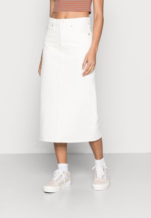 Hvid denim midi-nederdel med en lige pasform, der har frontlommer, høj talje og diskrete syningsdetaljer, kombineret med beige sneakers.