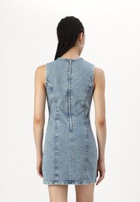Vestido de ganga sem mangas com silhueta ajustada, lavagem azul clara, costura visível, fecho de correr nas costas e barra reta.