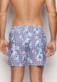 Costumi da bagno da uomo con un motivo floreale, caratterizzati da fiori blu e bianchi su uno sfondo geometrico rosa, con vita elastica e tasche laterali.
