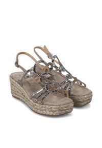 Sandalias de cuña con parte superior de ante beige, anillos metálicos decorativos y una plataforma envuelta en yute. Diseño de punta abierta con correa en el tobillo.