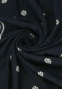 Sciarpa di tessuto blu navy con una texture liscia, decorata con motivi geometrici bianchi disposti a spirale.