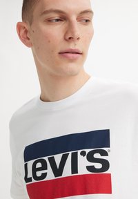Witte katoenen t-shirt met een opvallend Levi's logo in marineblauw en rood, met een klassieke ronde hals en korte mouwen.