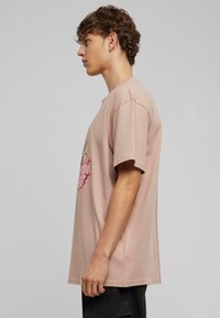 Kortærmet T-shirt i lyserød bomuld med et grafisk print på fronten. Har en afslappet pasform og blød tekstur.