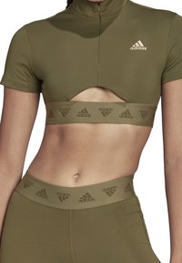 Olivgrön Adidas cropped topp med skärning under bröstet och matchande höga leggings med märkta elastiska midjeband.