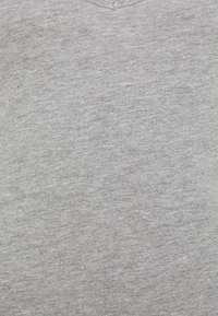 Ljusgrå v-ringad t-shirt gjord av mjukt bomullstyg, med en slät textur och en enkel, minimalistisk design utan mönster eller accenter.