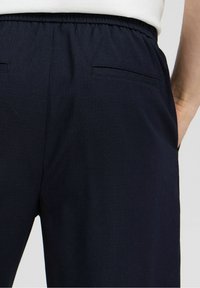 Námořnické modré kalhoty s elastickým páskem, které mají dvě zadní kapsy a strukturovanou látku pro získání většího zájmu.